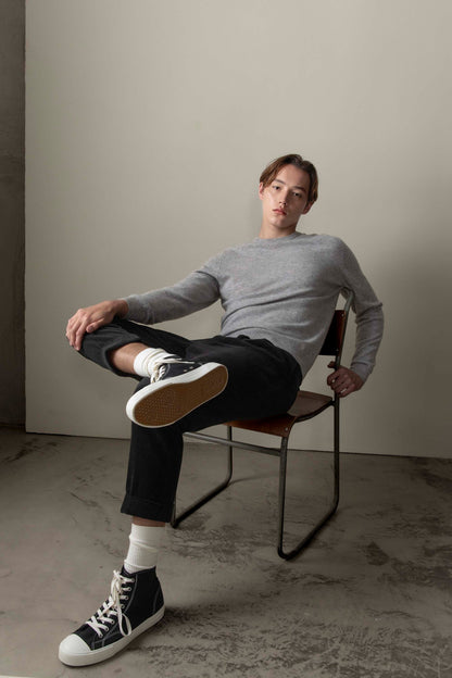 Men's Cashmere Crew Neck Jumper in light grey, slim relaxed fit, worn by model seated in a studio setting