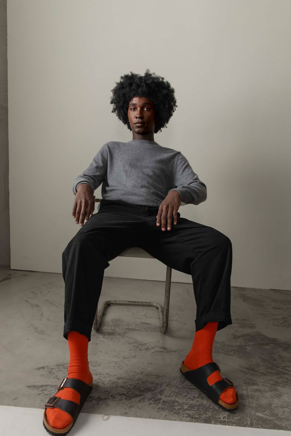 Men's Cashmere Crew Neck Jumper in Derby Grey, relaxed fit styled with black trousers, modelled seated in a studio