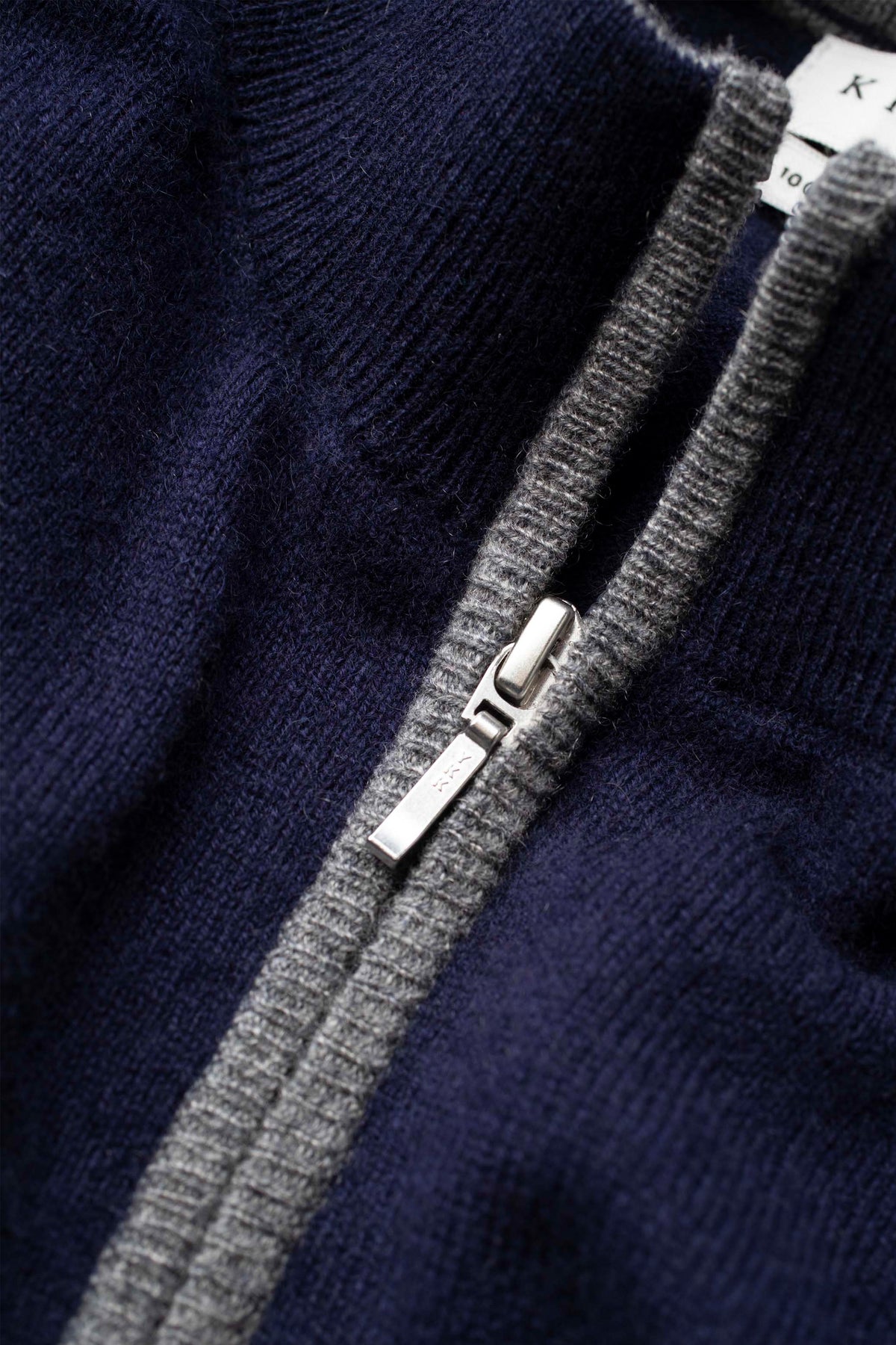 Close-up of silver zipper pull and grey contrast placket on Men's Half Zip Jumper in navy cashmere knit