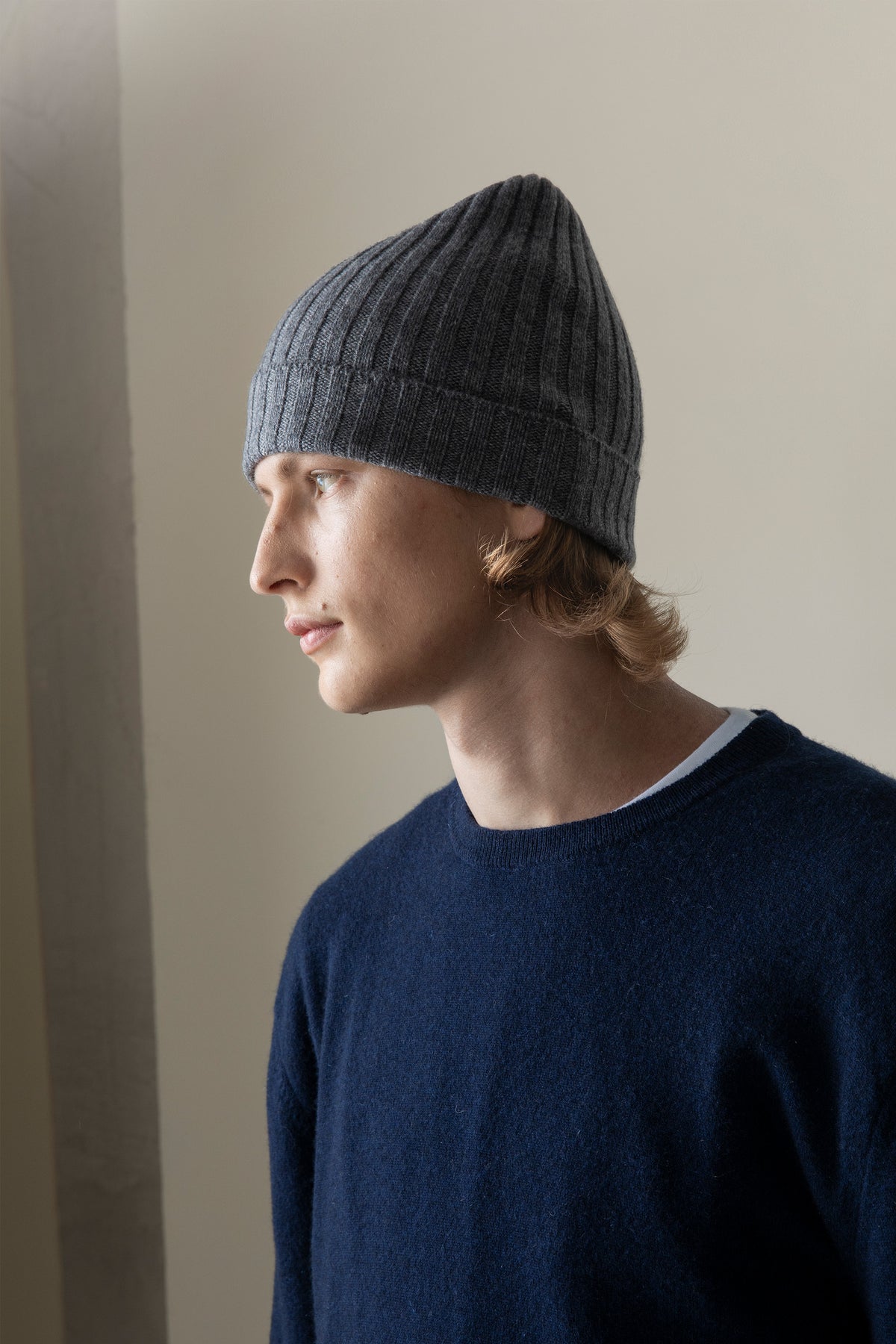 Unisex Cashmere Wide Ribbed Beanie Hat in Derby Grey shown in side profile on model, highlighting the ribbed texture and folded cuff