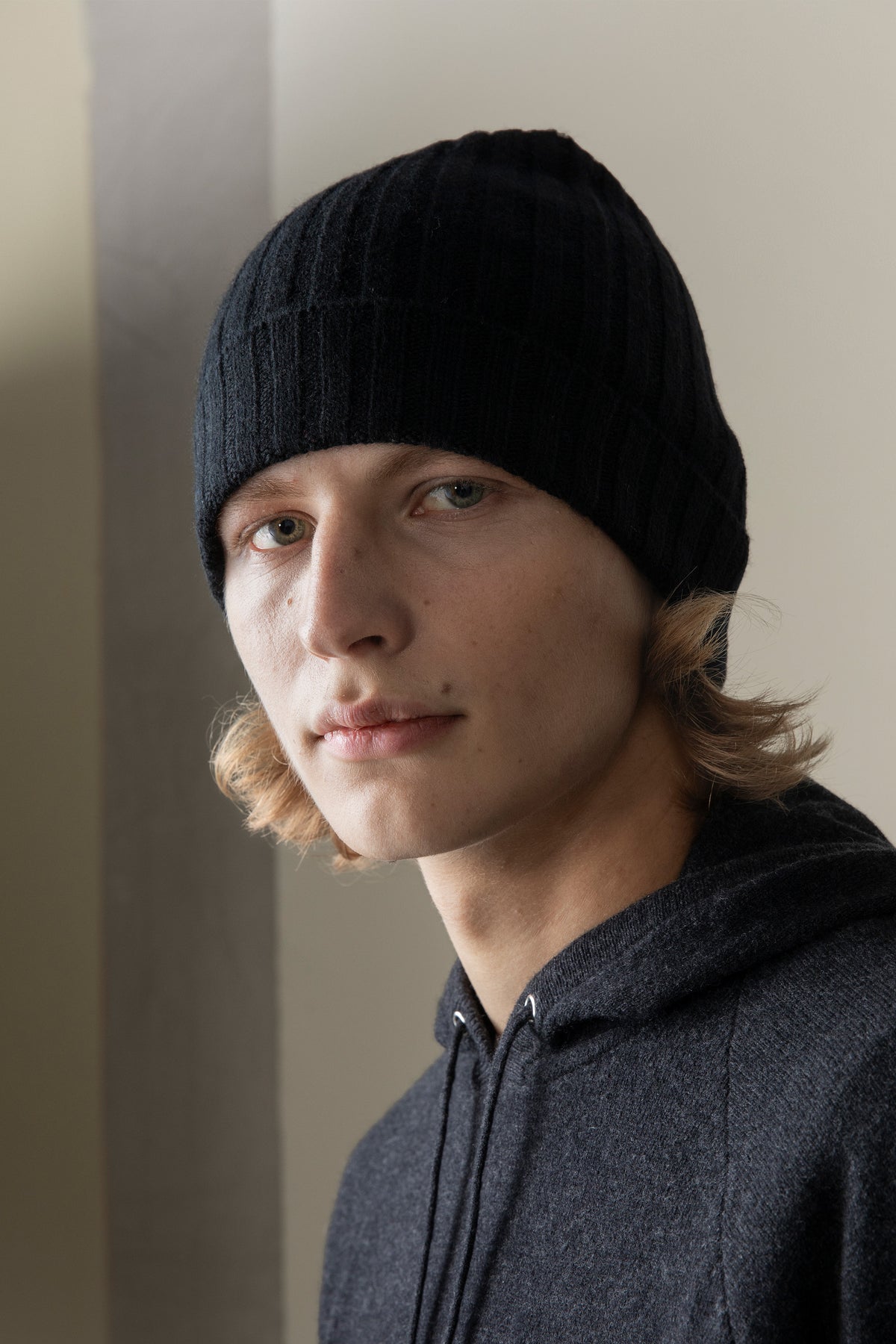 Model wearing the Unisex Cashmere Wide Ribbed Beanie Hat in black, front three-quarter view showing the folded brim and fit