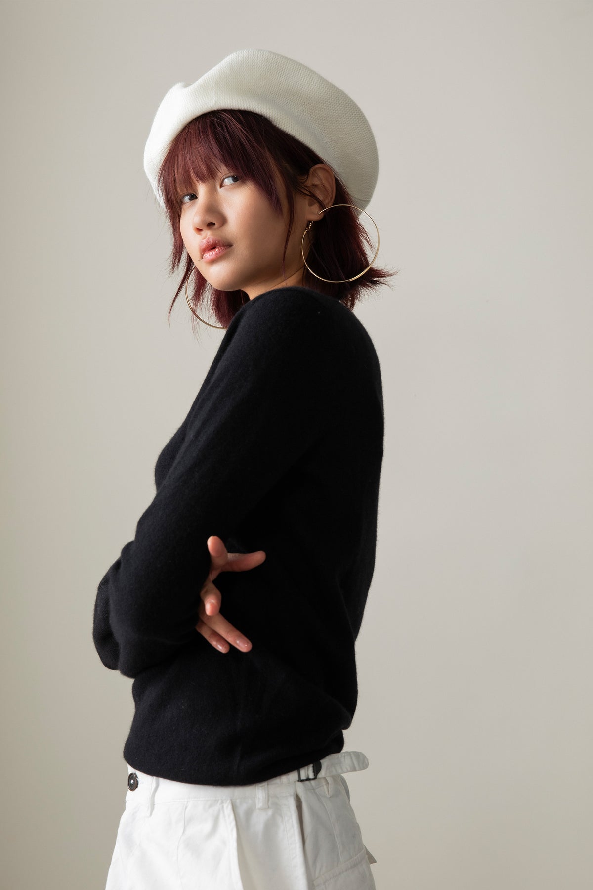 Cashmere Knitted Beret in Soft White styled at a slight angle on a model, shown from the side with a black sweater