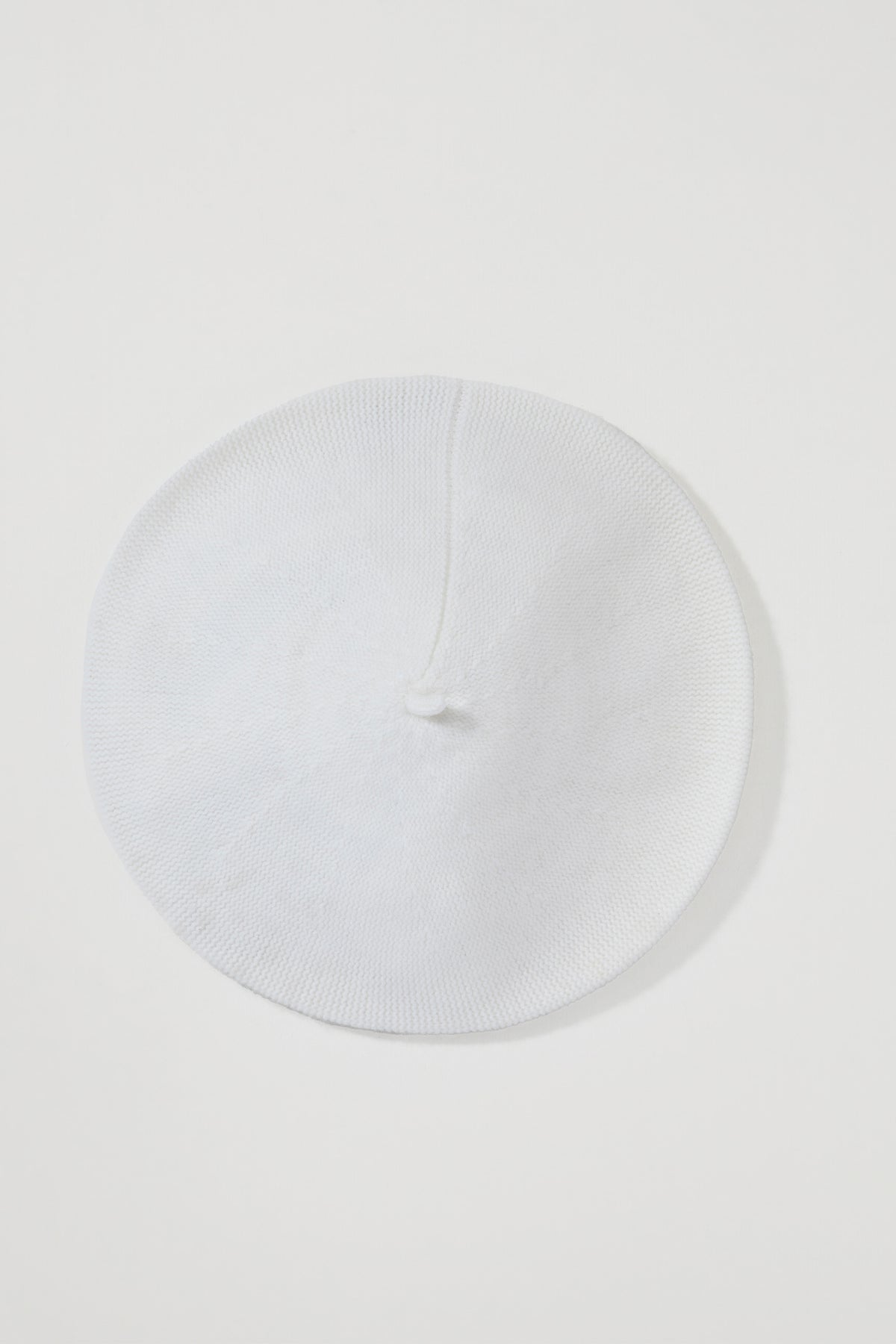 Top-down view of the Cashmere Knitted Beret in Soft White showing the centre nub and fine knit texture
