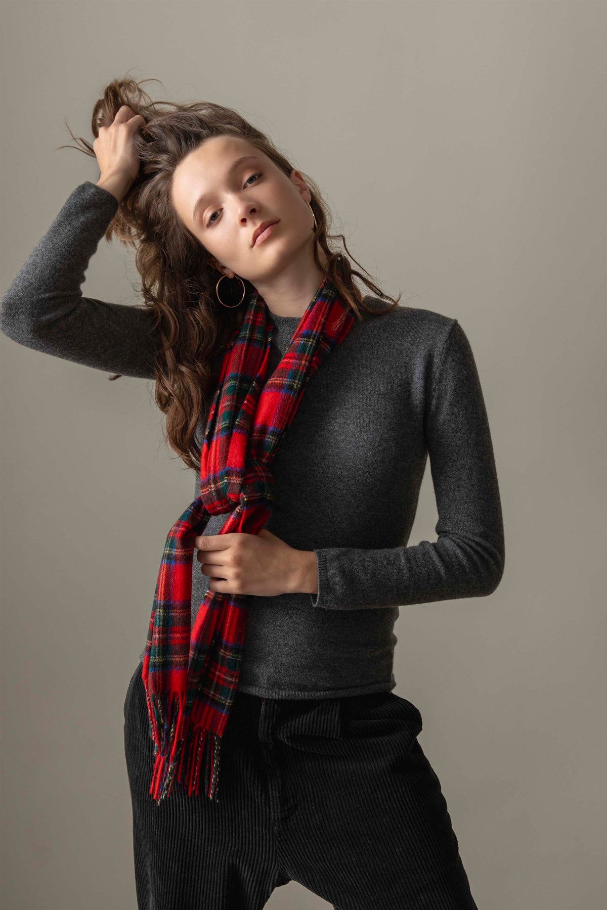 Made In Scotland Heritage Cashmere Scarf in Royal Stewart tartan worn loosely knotted over a charcoal sweater