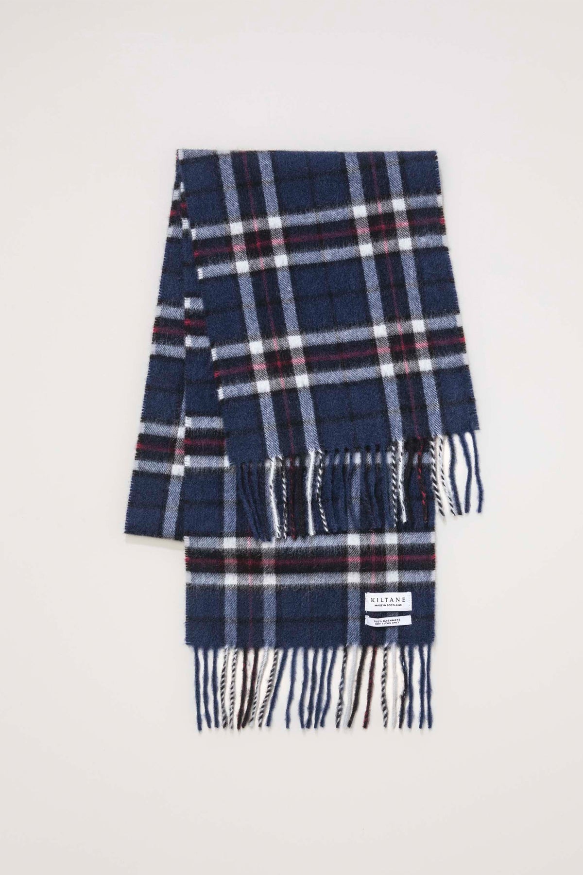 Kiltane Made In Scotland Scotty Thompson Cashmere Scarf in navy tartan plaid, folded flat showing brand label and fringed ends