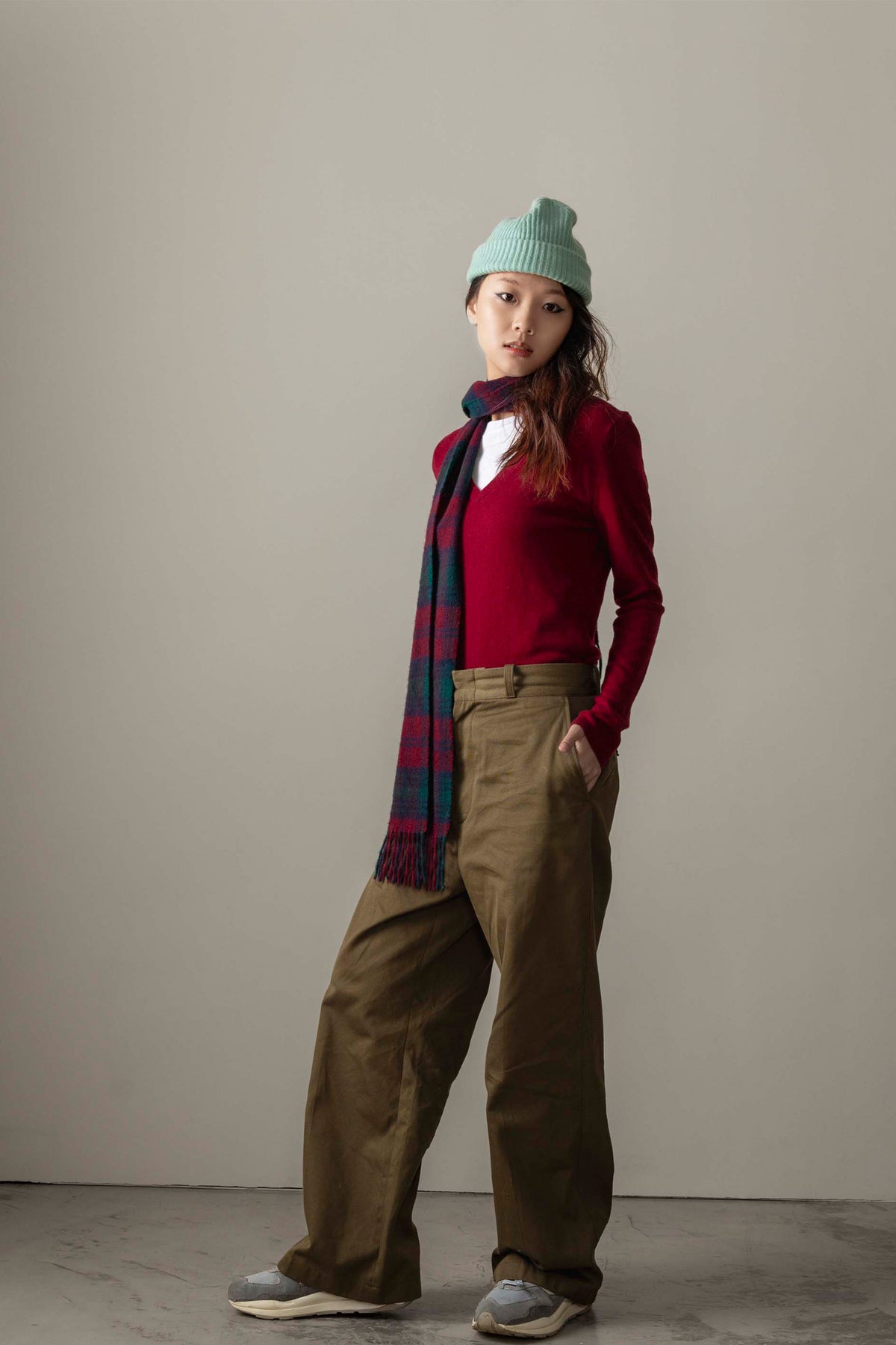 Made in Scotland Heritage Cashmere Scarf in Lindsay tartan styled over a red V-neck sweater, showing plaid pattern and fringed ends