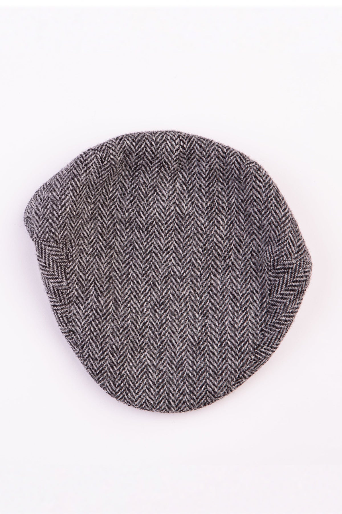 Harris Tweed Stornoway Cap in light grey herringbone — top-down view showing the flat crown and tweed weave pattern