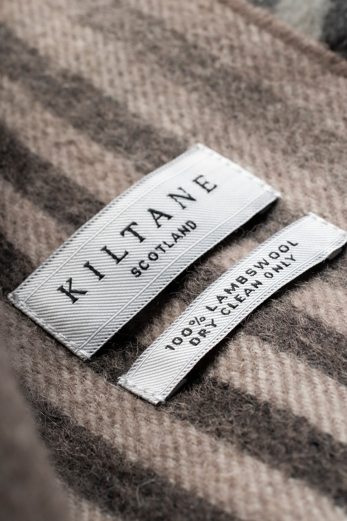 Close-up of Kiltane Scotland label on Contemporary Check Lambswool Scarf showing 100% lambswool dry clean only care tag