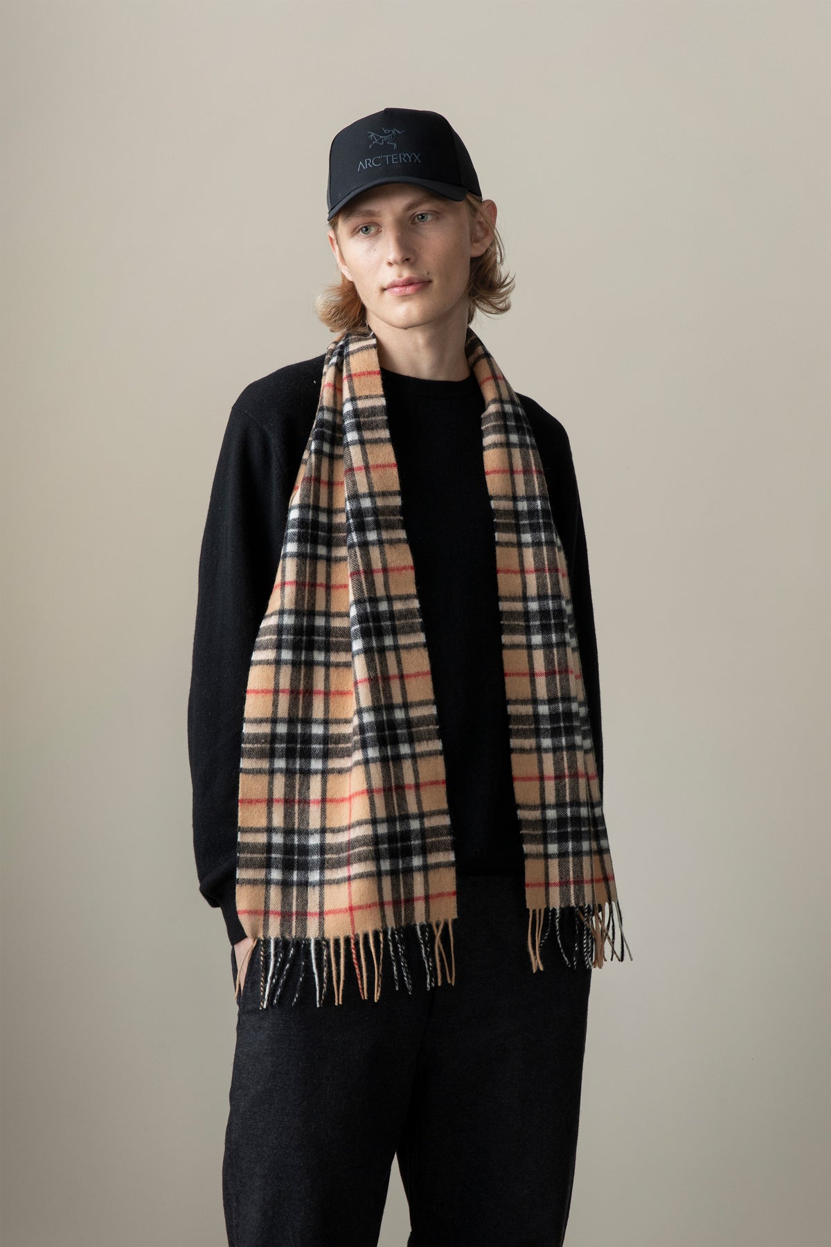 Scotty Thompson Lambswool Scarf in Camel draped over a model, featuring classic tan plaid with black, white, and red stripes and fringed ends