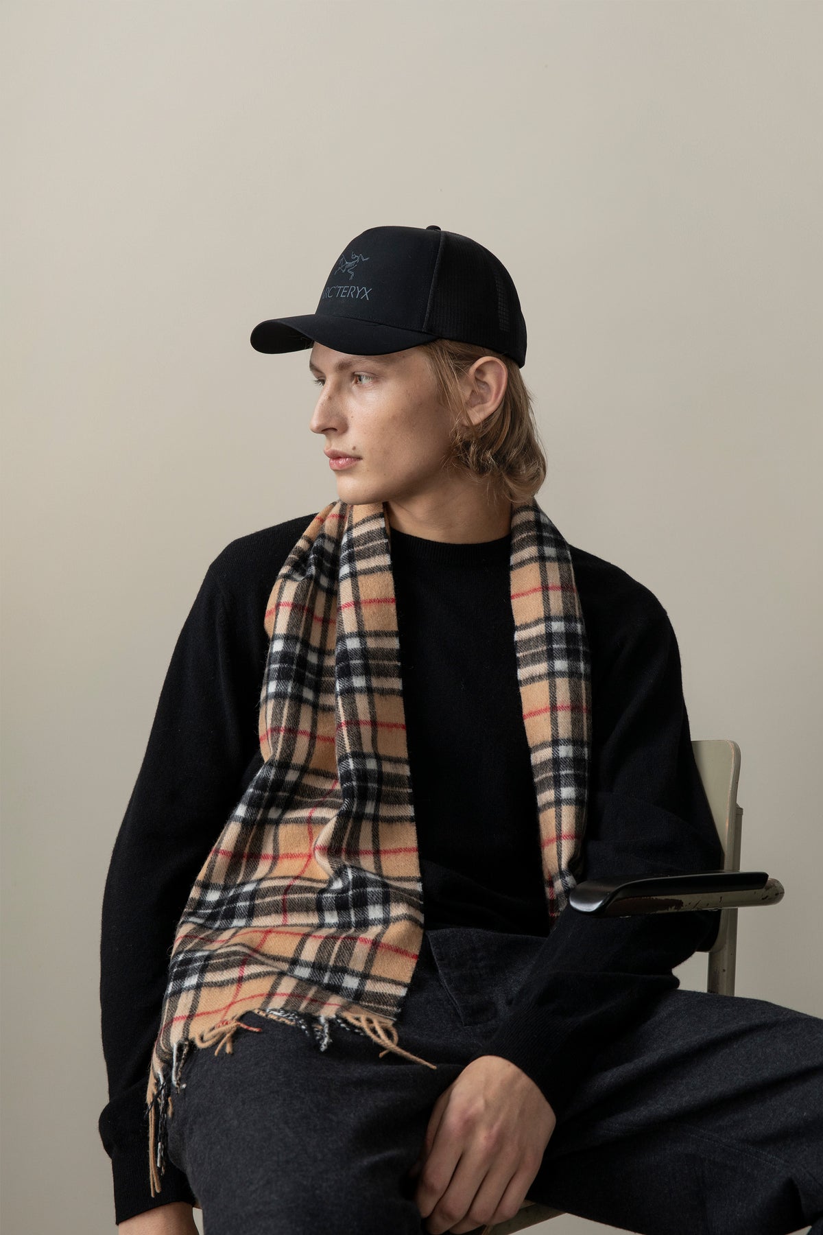 Scotty Thompson Lambswool Scarf in Camel worn draped over a black sweater, showing the classic tartan plaid pattern with fringed ends