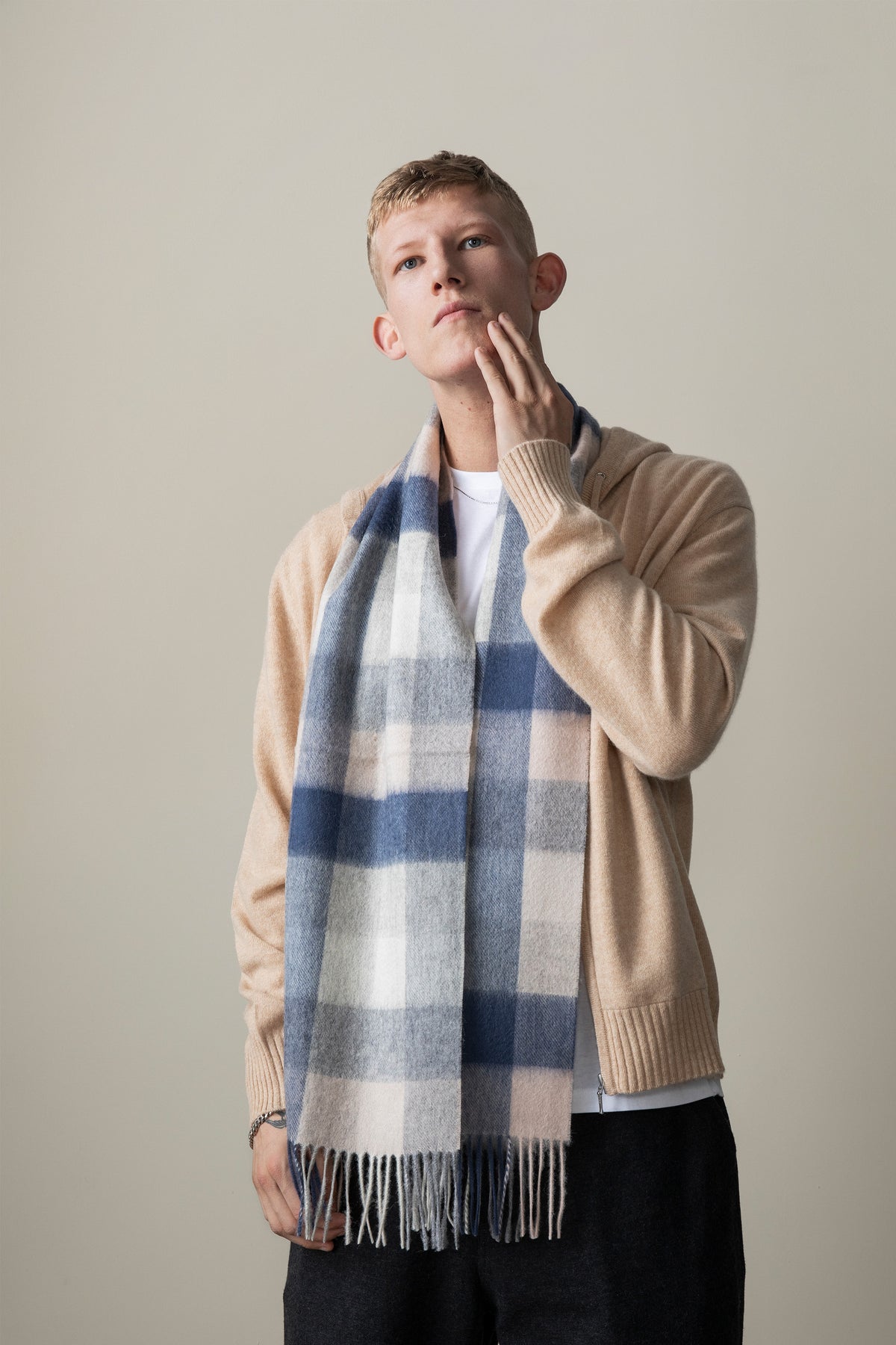 5 Square Check Lambswool Scarf in Swiss Coffee worn draped over a camel cardigan, showing blue and cream check pattern with fringe detail