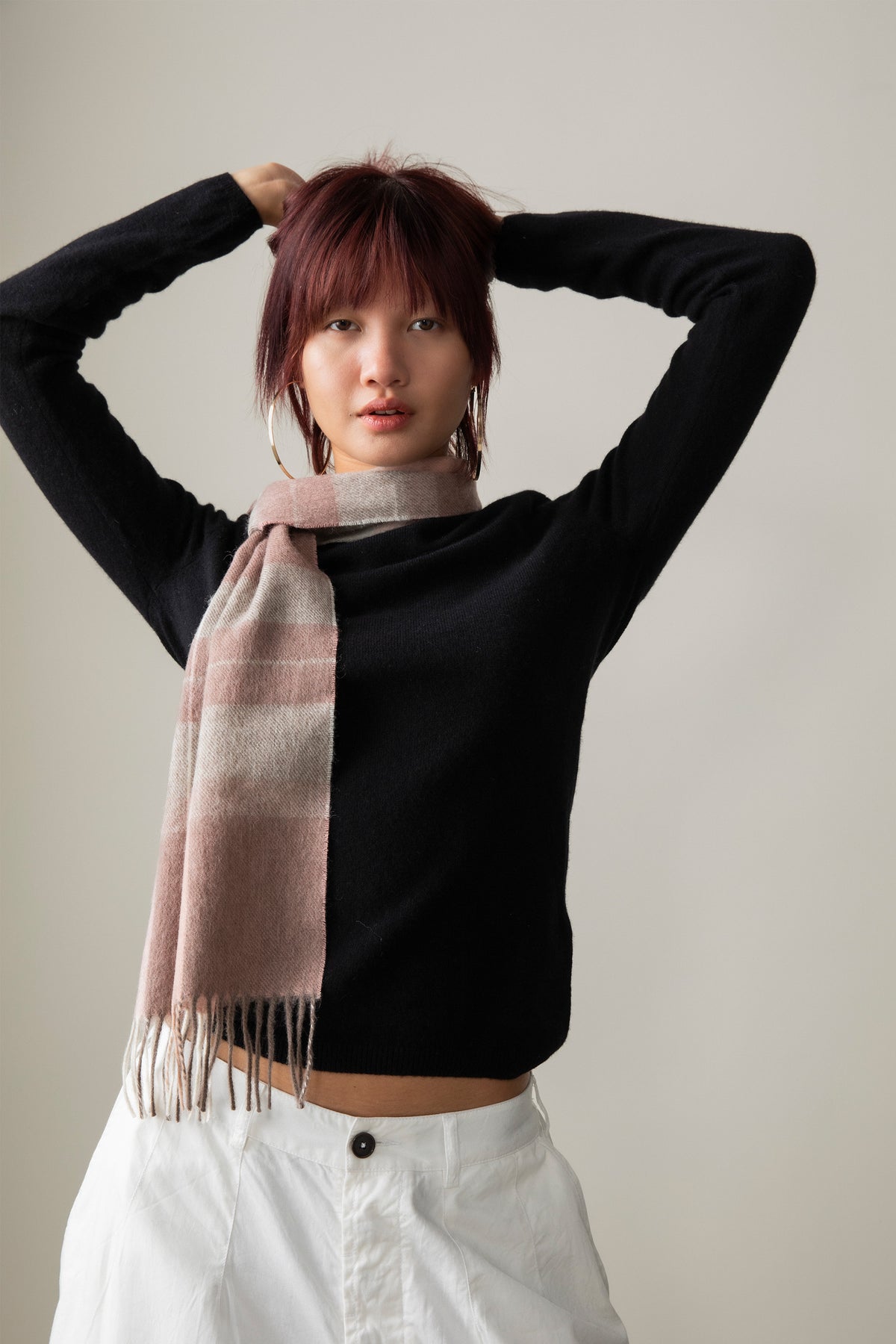 Contemporary Check Lambswool Scarf in Cameo worn loosely around the neck, showing soft pink and cream check pattern with fringed ends