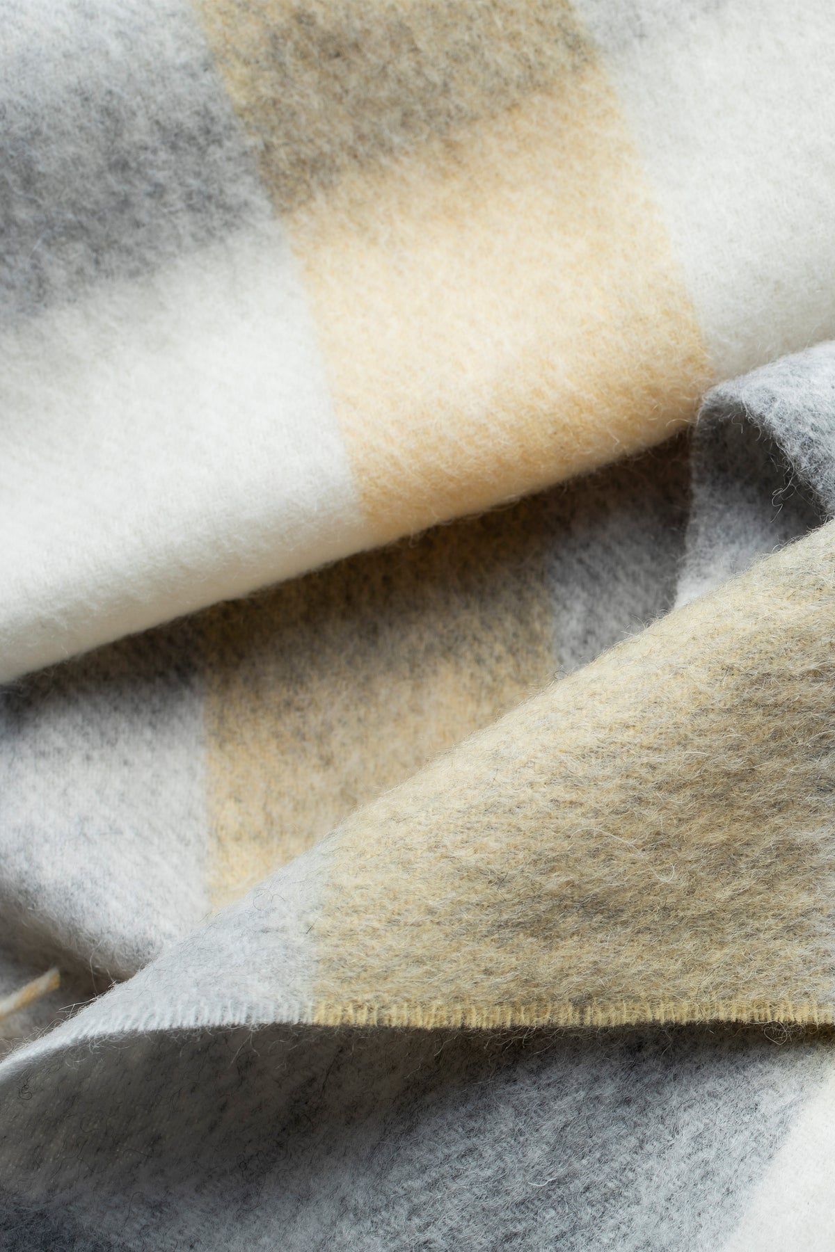 Close-up of 5 Square Check Lambswool Scarf in Butter showing soft brushed texture in cream, gold, and grey check pattern