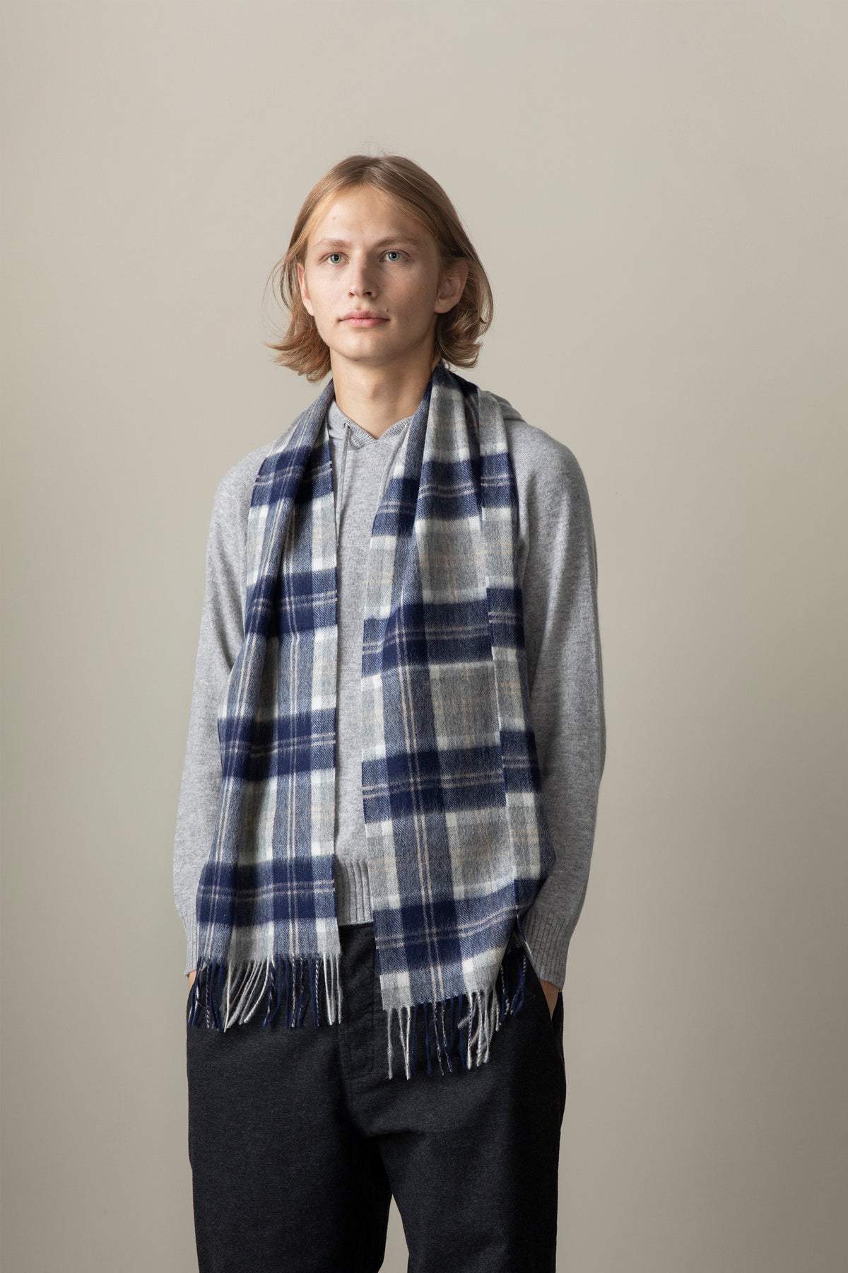 Heritage Tartan Lambswool Scarf in Silver Bannockbane worn draped over a grey sweater, showing navy and cream plaid pattern with fringe