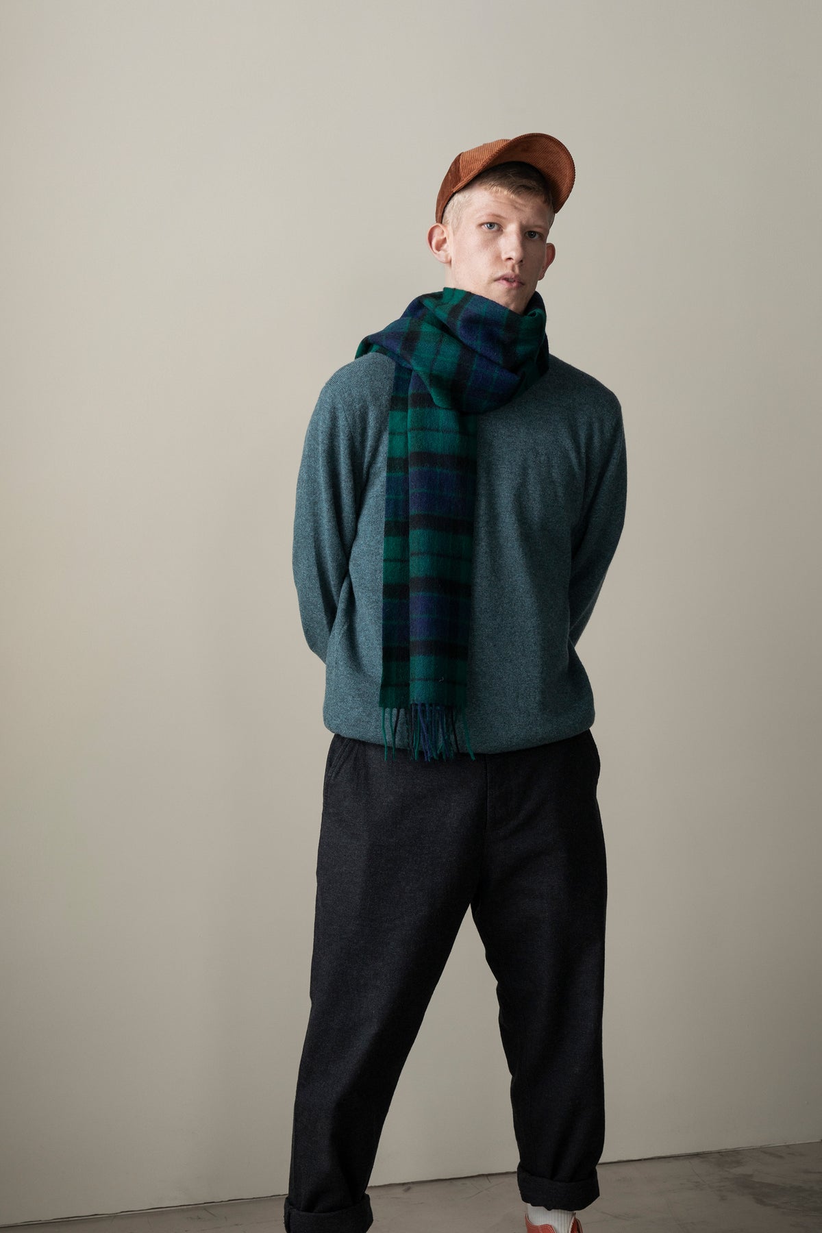 Heritage Tartan Lambswool Scarf in Blackwatch worn loosely draped over one shoulder with fringed ends visible, styled with a grey sweater