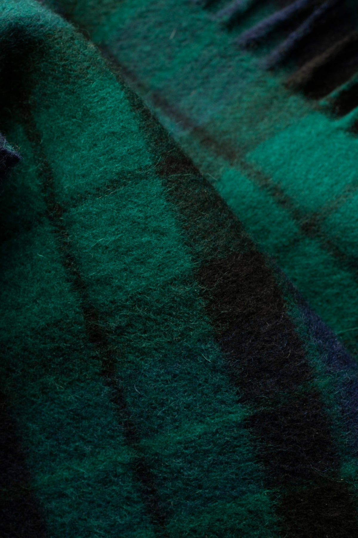Close-up of Heritage Tartan Lambswool Scarf in Blackwatch showing soft brushed wool texture and deep green and navy plaid pattern