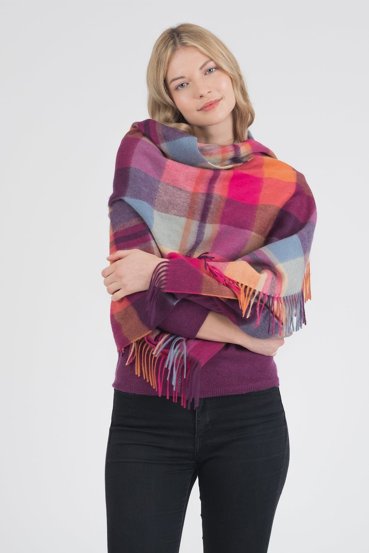 Model wearing Square Check Lambswool Stole - Orient Ginger wrapped around shoulders, showing plaid pattern in pink, purple, orange, and blue with fringed edges