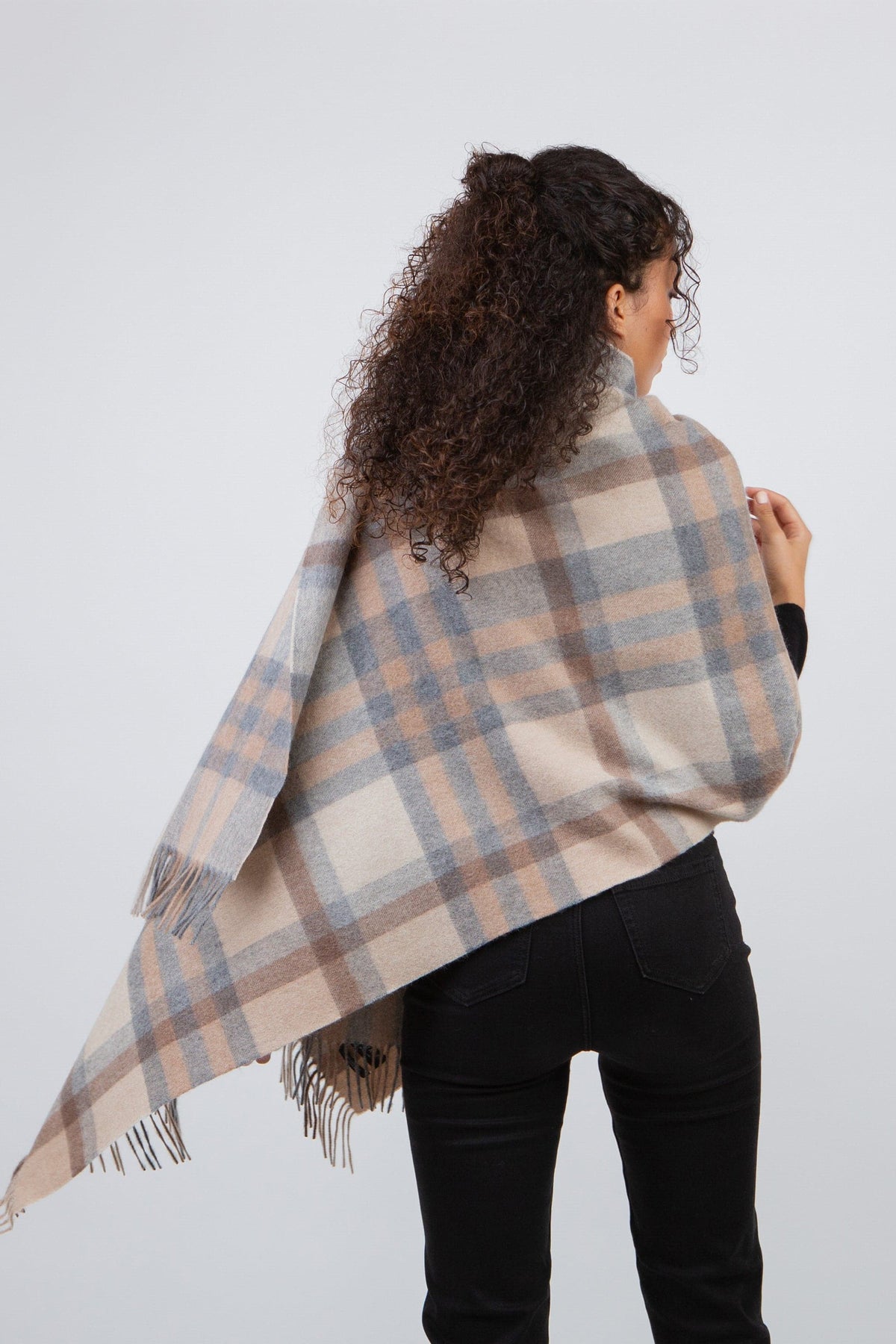 Back view of model wearing Tartan 2 Lambswool Stole in Natural, showing full plaid pattern in cream, blush, and grey with fringed edges