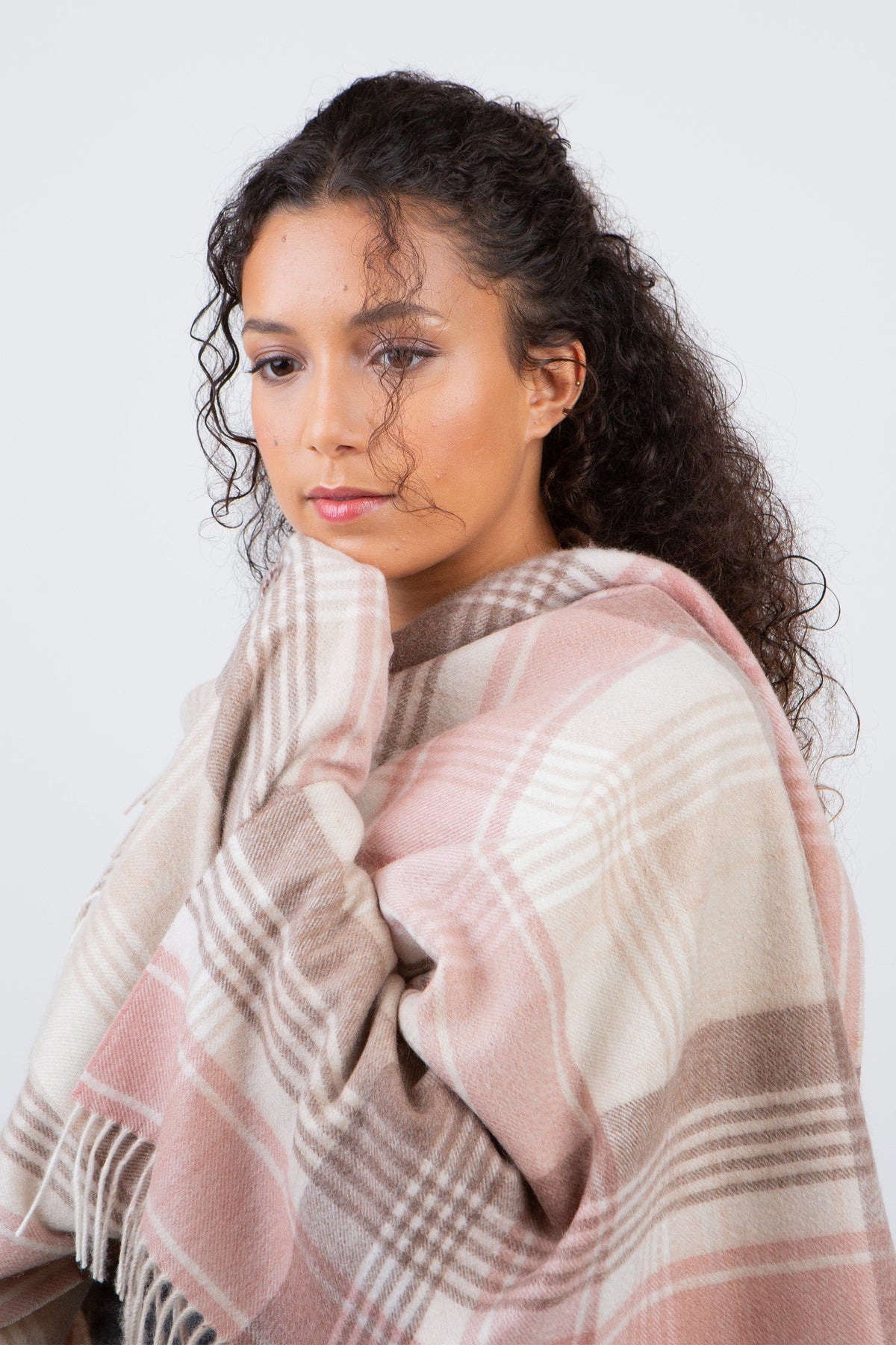 Repeat Edge Lambswool Stole in Natural, a soft plaid wrap in pink, cream, and taupe tones with fringed edges, modelled draped over shoulders
