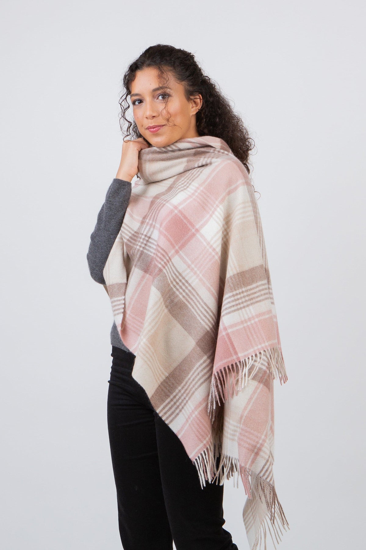 Repeat Edge Lambswool Stole in Natural worn draped over shoulders, showing pink, cream, and taupe plaid pattern with fringed edges