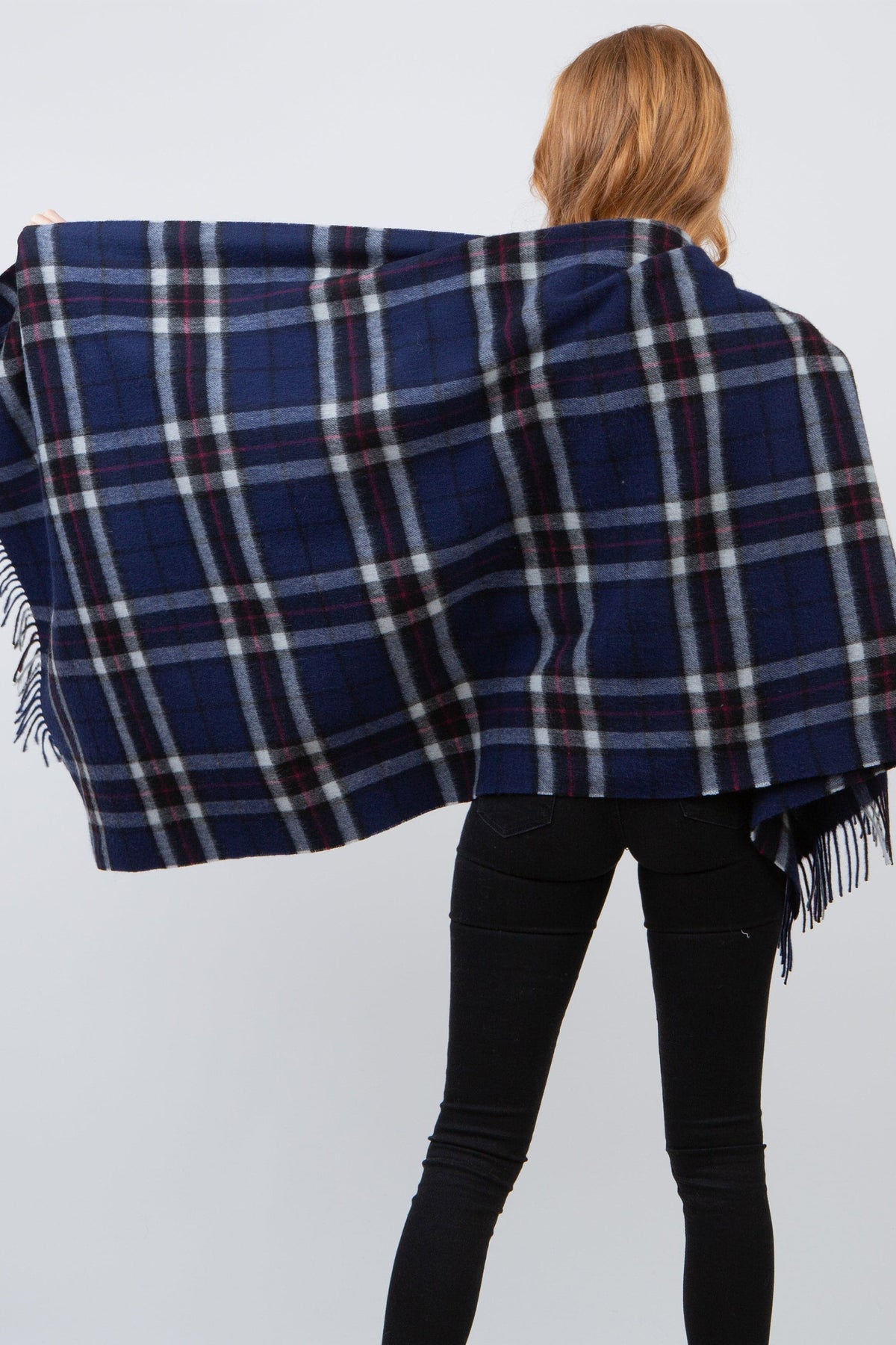 Back view of model holding open the Scotty Thompson Lambswool Stole in Navy, showing full tartan plaid pattern and fringed edges