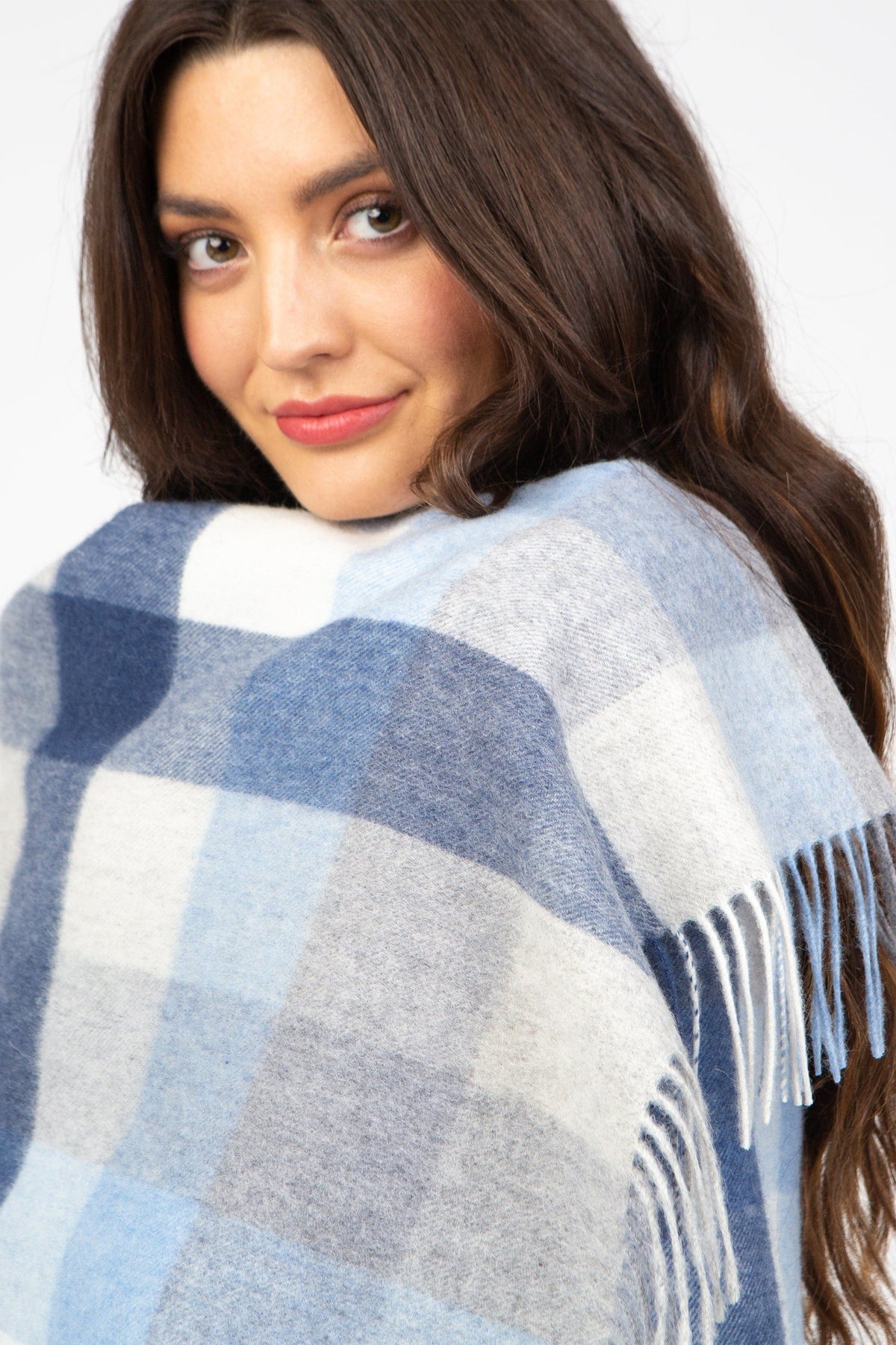 5 Square Check Lambswool Stole in Glacier wrapped around shoulders, showing blue and white check pattern with fringed edge