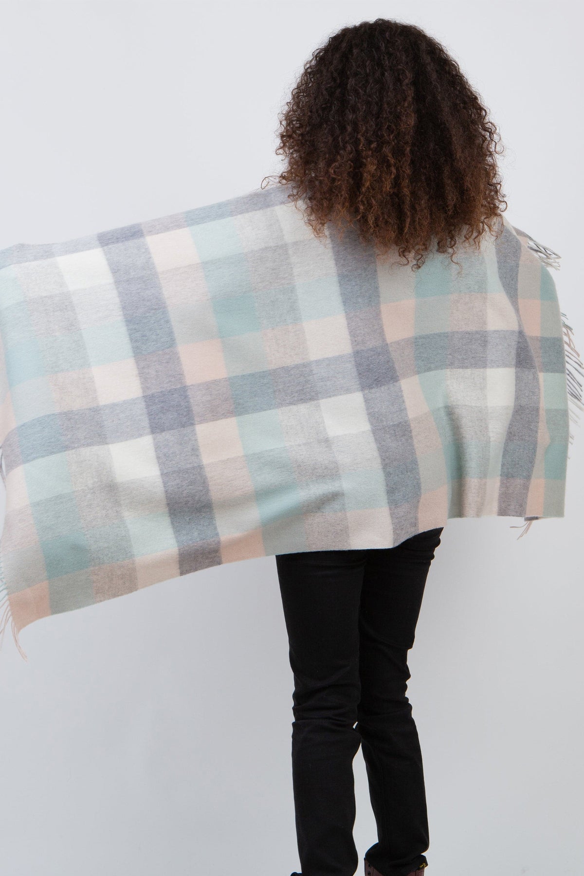 Back view of model wearing 5 Square Check Lambswool Stole in Brume, showing the pastel plaid pattern in mint, grey, and blush tones