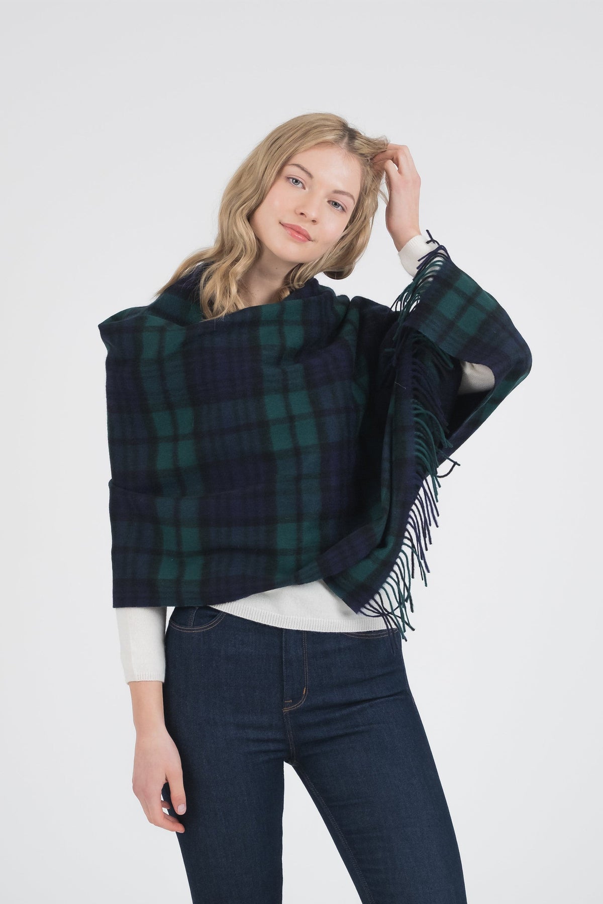 Model wearing Heritage Tartan Lambswool Stole in Blackwatch draped over shoulders, showing green and navy plaid pattern with fringe detail
