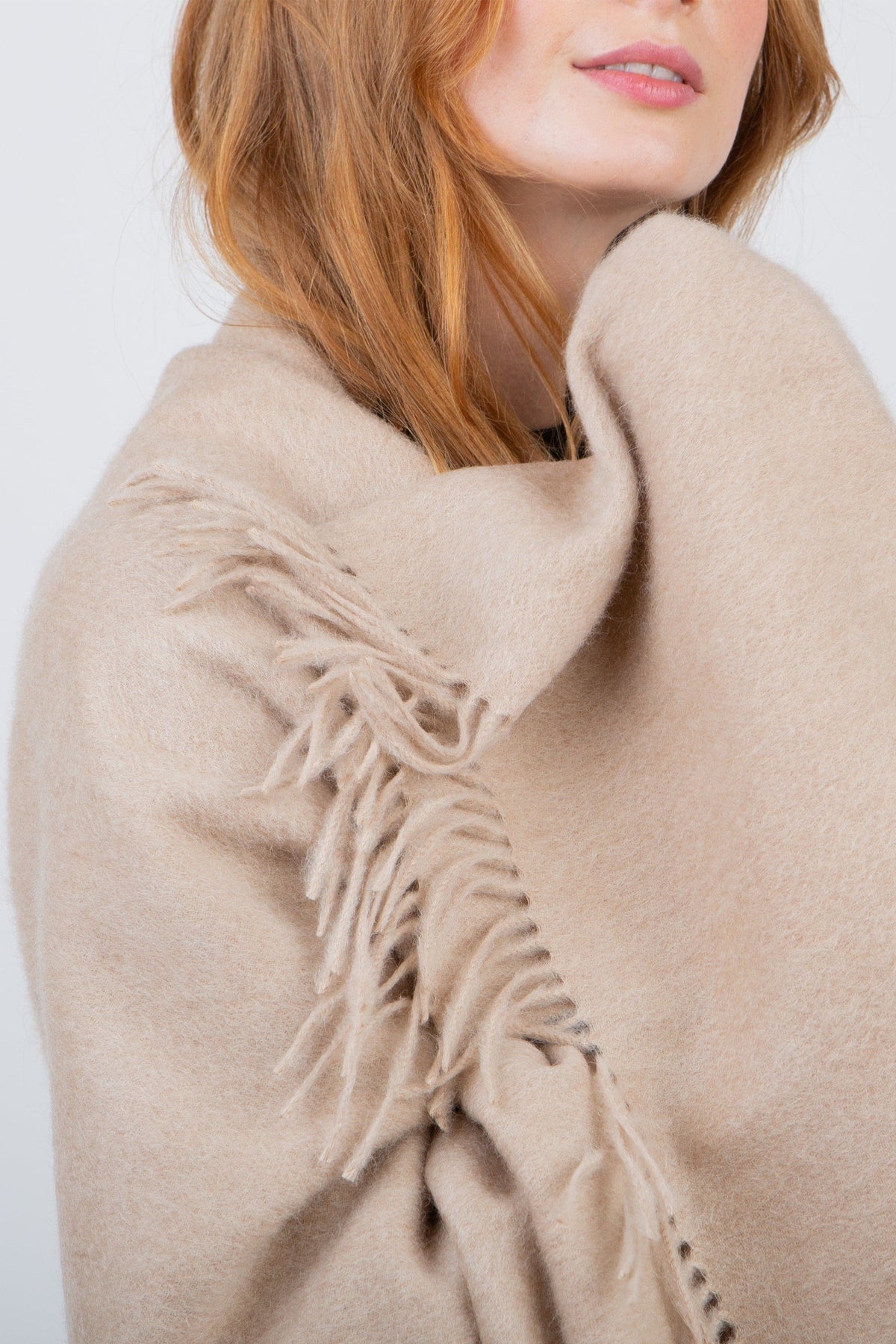 Close-up of Solid Lambswool Stole in Vicuna showing soft brushed texture and fringed edge detail draped over shoulder