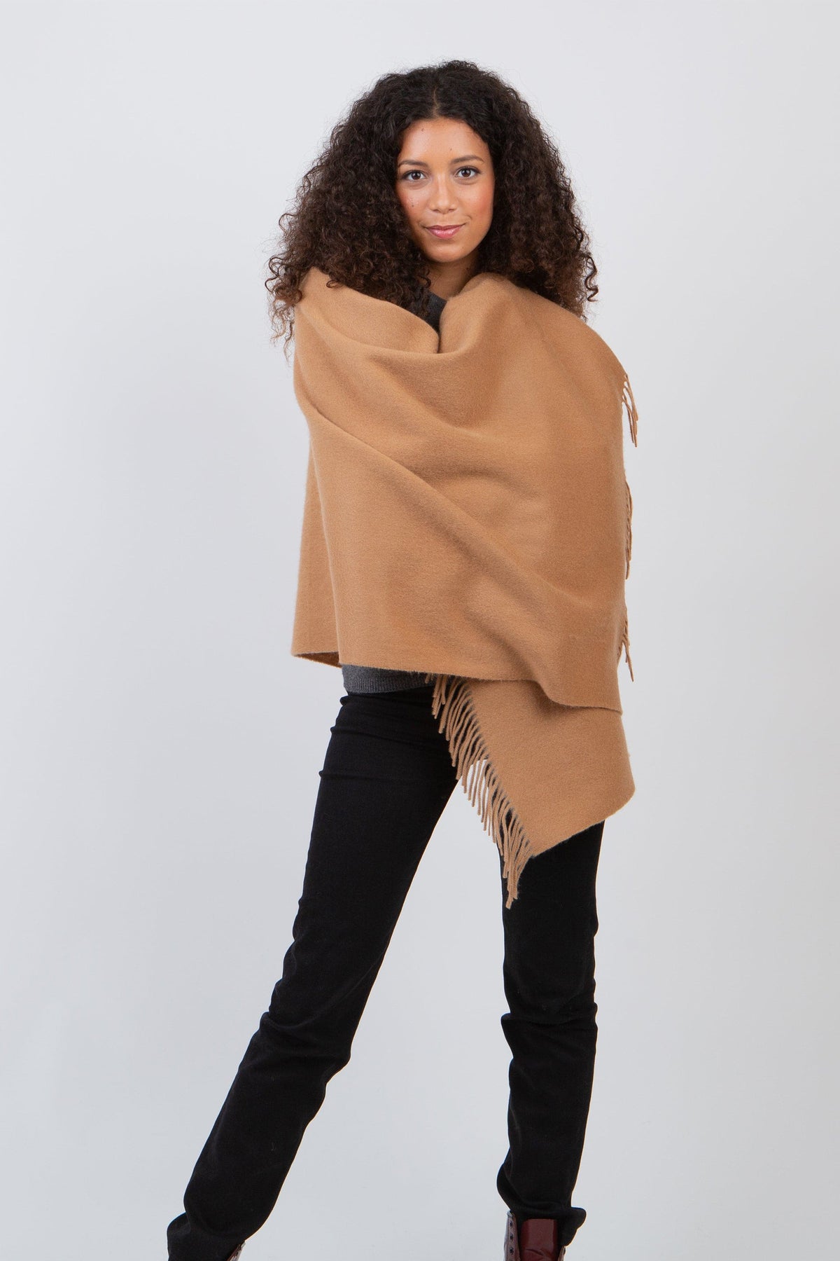 Solid Lambswool Stole in Dark Camel worn wrapped around shoulders, showcasing soft wool texture and fringed edges