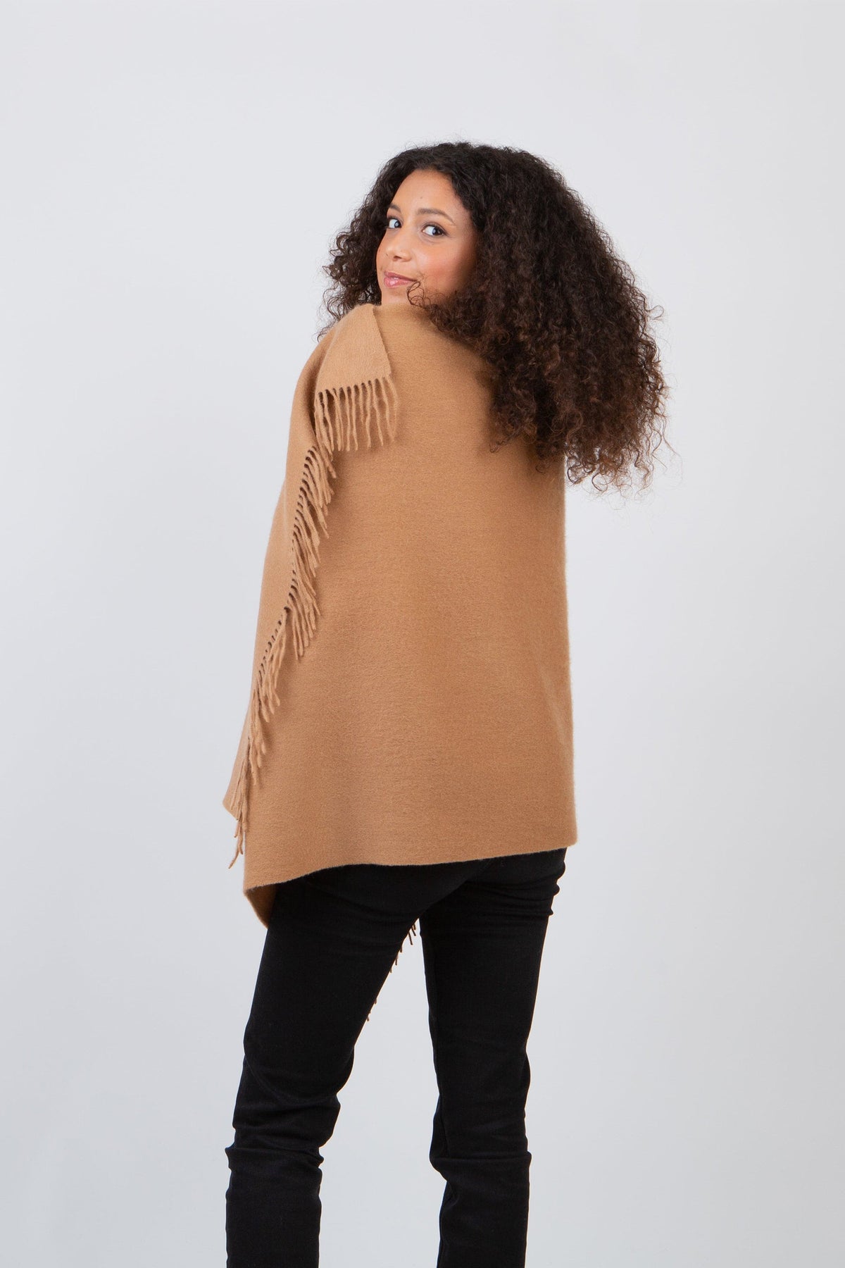 Back view of the Solid Lambswool Stole in Dark Camel worn as a wrap, showing fringe trim along the edges