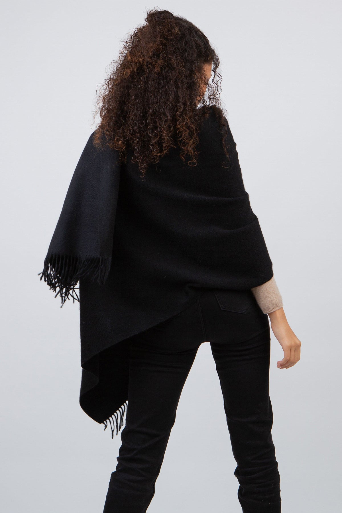 Back view of the Solid Lambswool Stole in black draped over shoulders, showing fringed edges and relaxed wrap styling