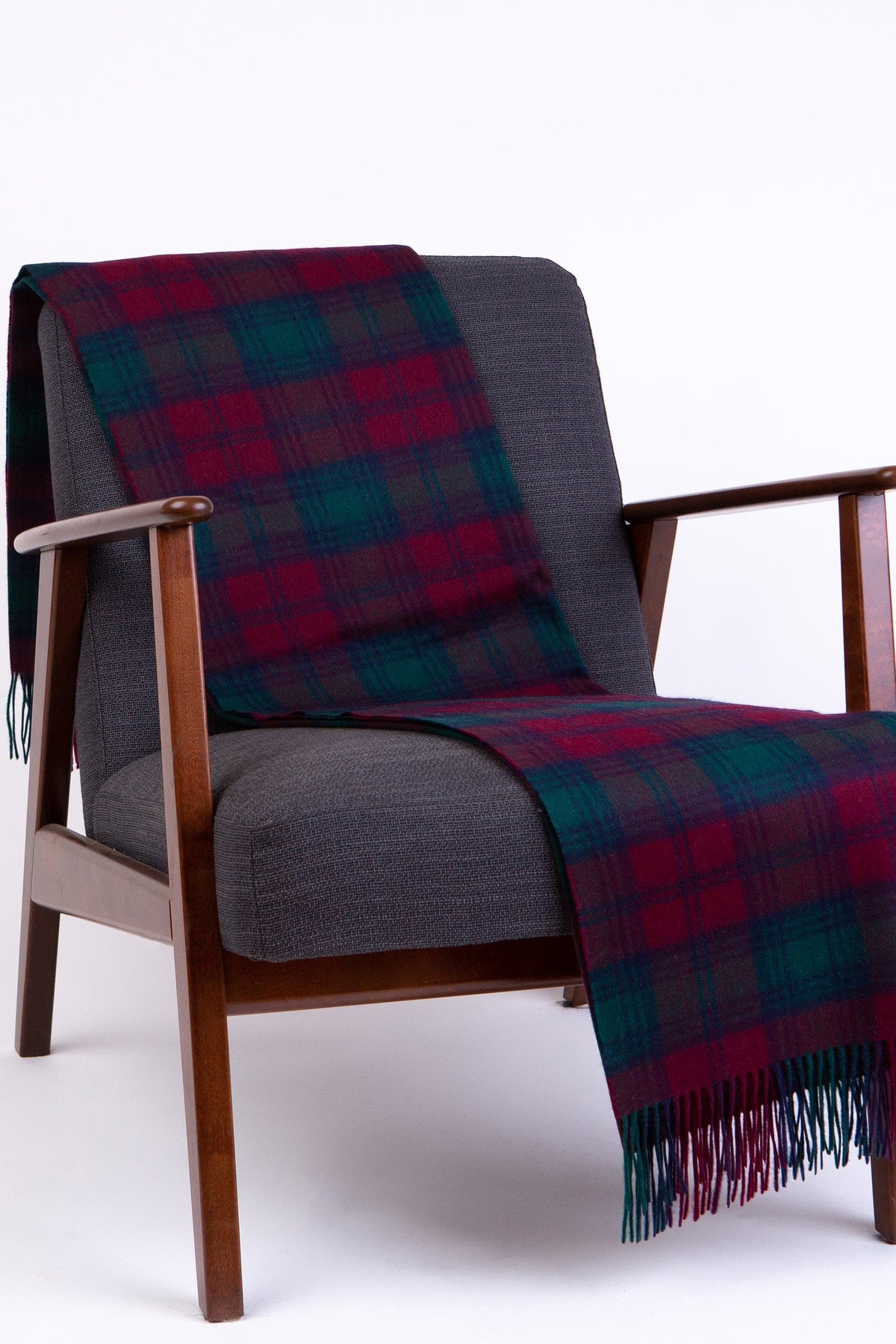 Lambswool Throw - Lindsay in burgundy and teal tartan draped over a mid-century armchair, showing fringed edge detail
