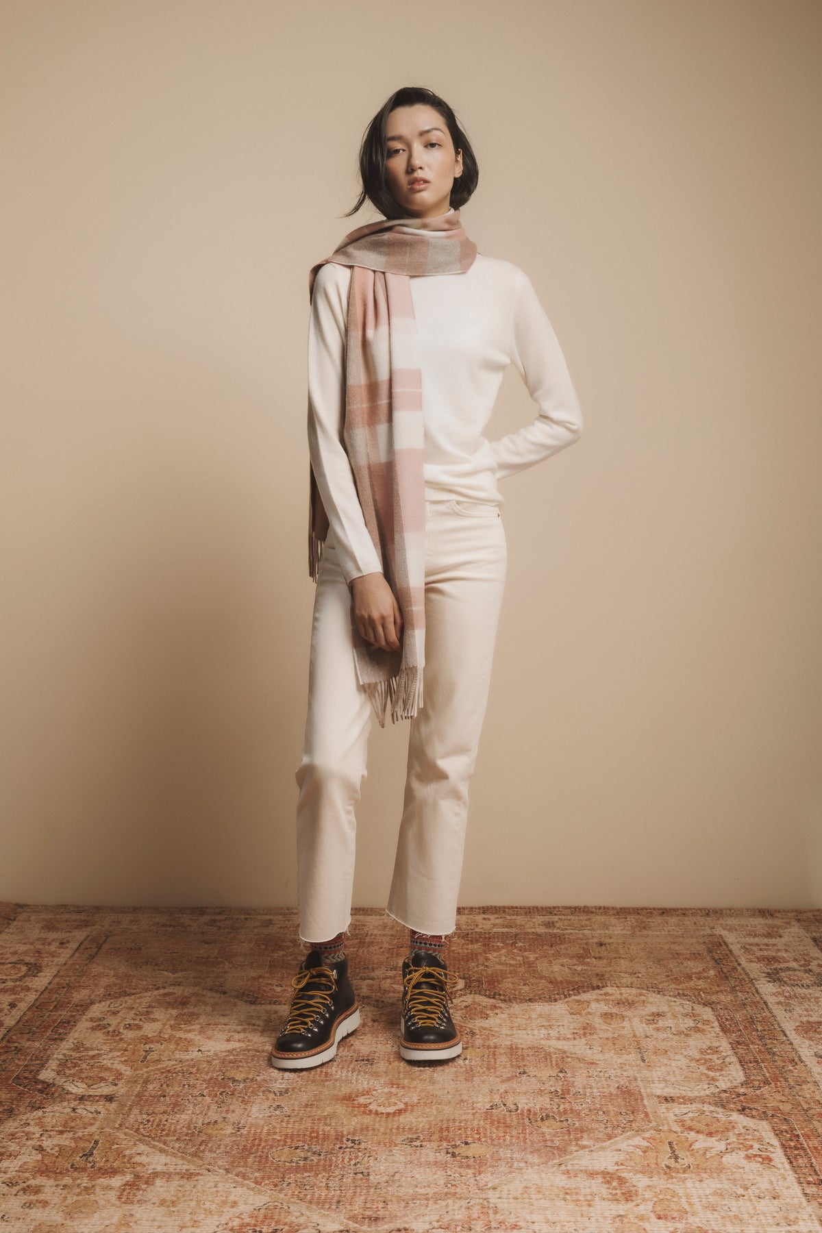 Contemporary Check Cashmere Wide Scarf in Cameo Check styled on model with fringed ends draping over a cream sweater and white jeans