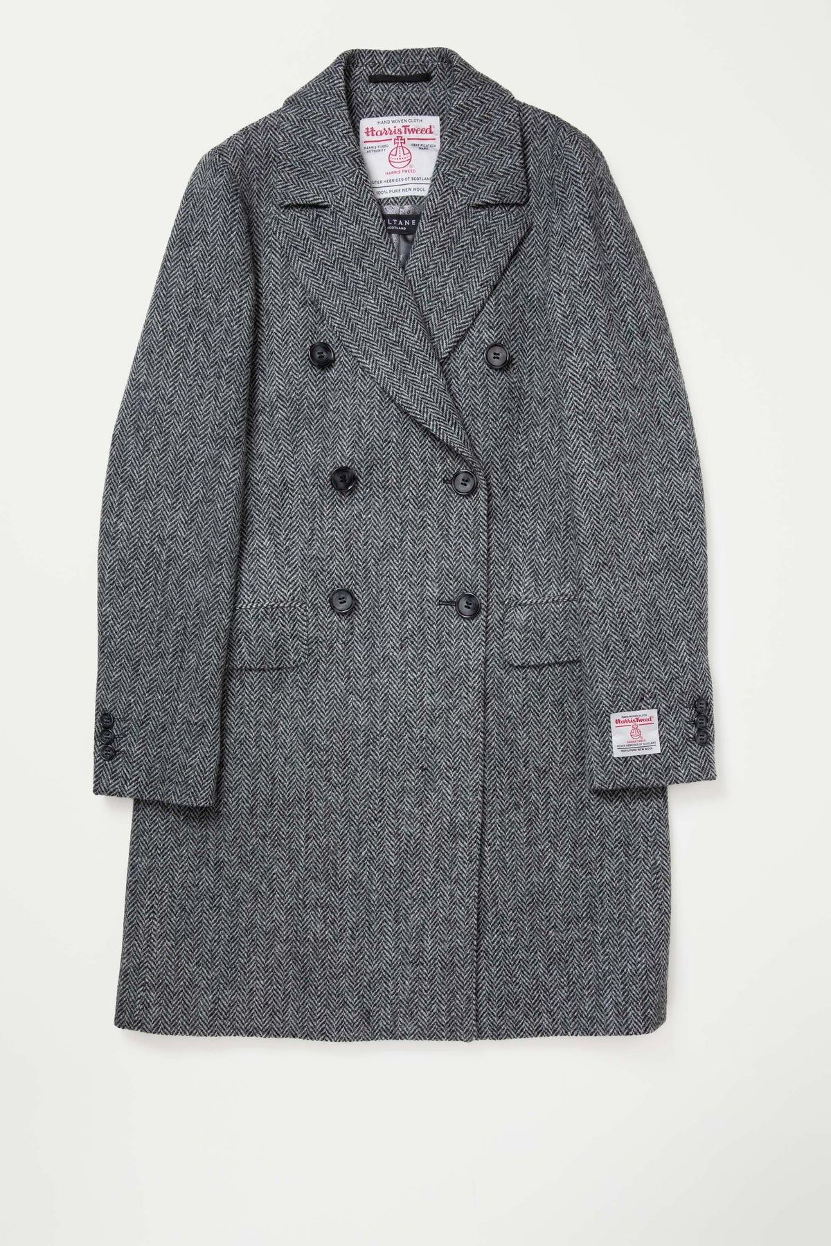 Women's Harris Tweed Melody Coat in light grey herringbone laid flat, showing double-breasted front with Harris Tweed certification labels