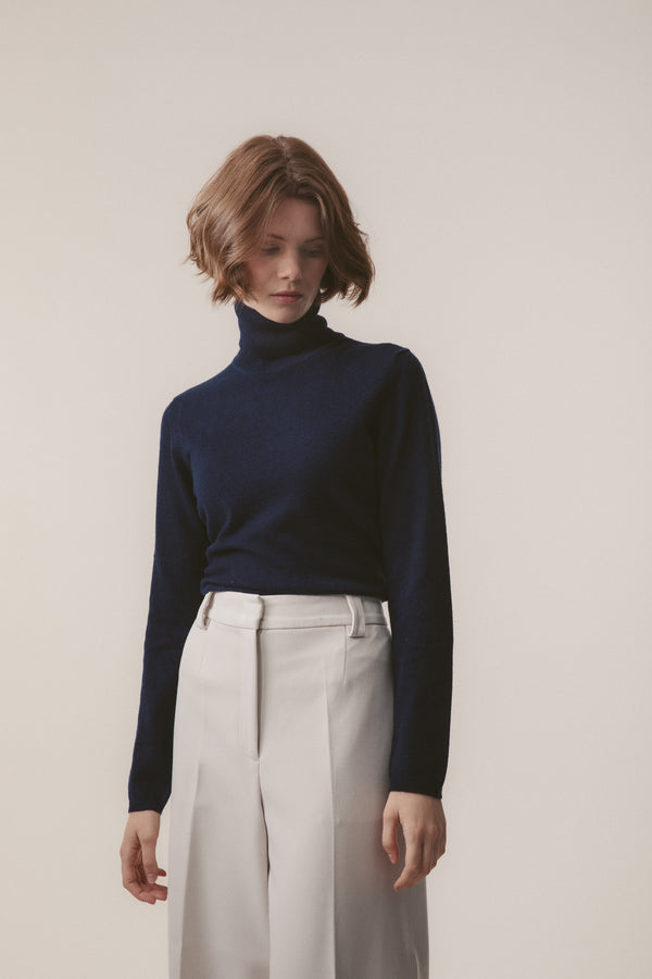Women's Cashmere Polo Neck Jumper in Cosmos navy blue, lightweight slim fit styled tucked into white trousers
